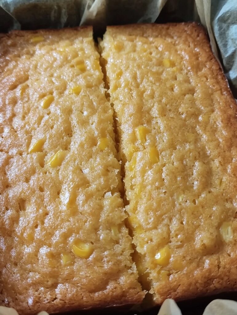 Pan de elote casero sin harina recién horneado, con textura jugosa y granos de maíz visibles.
