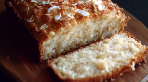 Pan de banana avena y coco casero recién horneado en molde, con textura húmeda y esponjosa, decorado con coco rallado y rodajas de banana