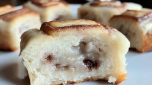 Freshly baked keto cinnamon buns with sugar-free glaze drizzled on top, arranged in a round baking dish on a wooden surface