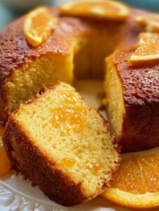 Bizcocho de naranja casero decorado con rodajas de naranja, con una rebanada servida en primer plano