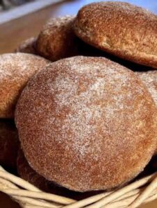 Semitas integrales recién horneadas espolvoreadas con piloncillo, en una canasta de mimbre.
