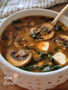 Tazón de sopa de champiñones con espinaca, chipotle y cubos de queso panela.