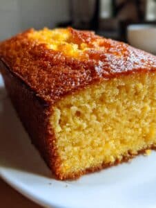 Pastel de elote y canela sin harina, recién horneado, servido en un plato junto a una taza de café.