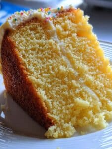 Torta clásica de vainilla casera recién horneada sobre una mesa de madera, decorada con azúcar glas y ralladura de limón.