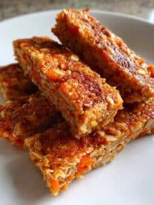Barritas energéticas caseras de zanahoria, avena y coco sobre un plato blanco.