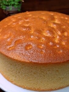 Pastel casero de leche condensada, esponjoso y dorado recién horneado sobre un plato blanco.