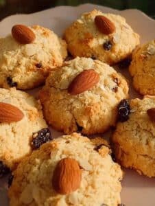 Galletas de almendra saludables caseras, doradas y crujientes, decoradas con almendras enteras y pasas.
