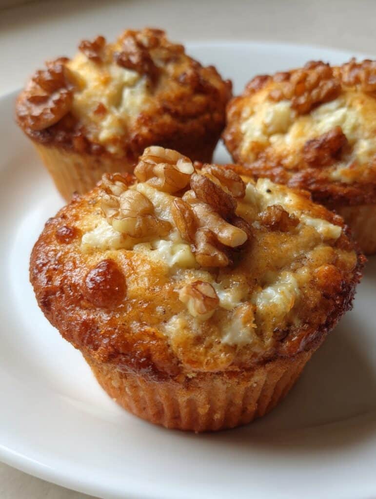 Muffins saludables de cottage con manzana verde y nuez recién horneados sobre un plato blanco.