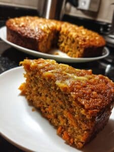 "Rebanada de bizcocho de naranja y zanahoria con avena, esponjoso y casero, servido en un plato blanco."