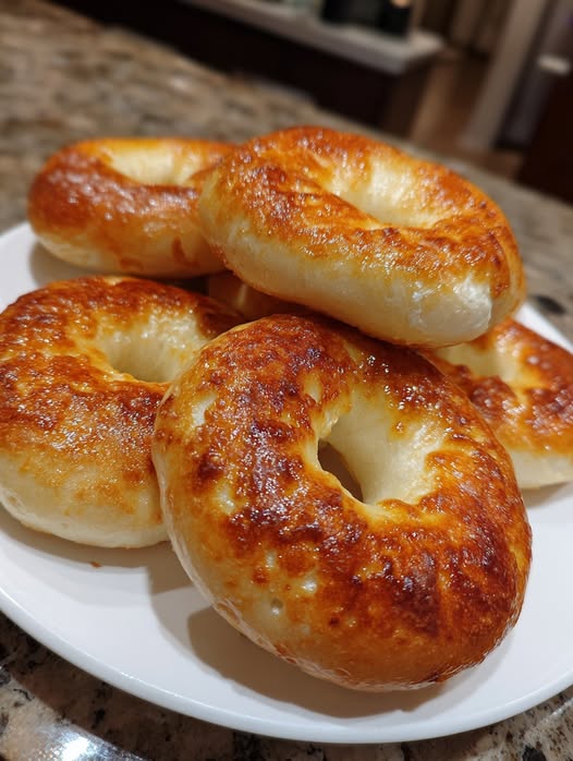 Golden brown, low-carb cottage cheese bagels stacked on a white plate — soft, fluffy, and perfectly baked.