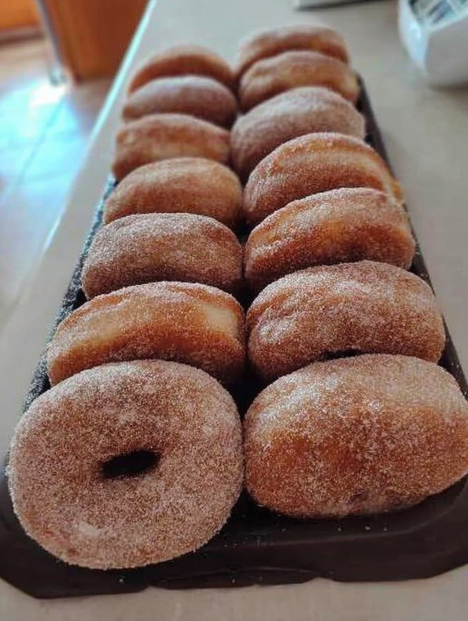 Donas caseras espolvoreadas con azúcar, hechas con masa esponjosa para pan dulce.