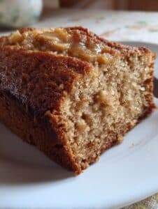 Rebanada de panqué de manzana y canela casero, con textura esponjosa y trozos de manzana caramelizada por encima.