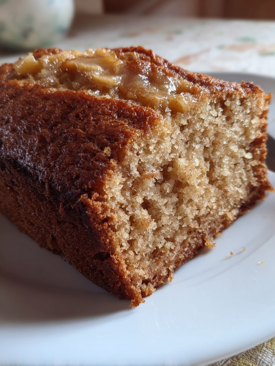 Rebanada de panqué de manzana y canela casero, con textura esponjosa y trozos de manzana caramelizada por encima.