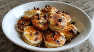 Chocolate chip cottage cheese pancake bites arranged on a plate, showing fluffy golden mini pancakes with visible chocolate chips, photographed in natural lighting