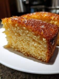 Bizcocho de naranja y avena sin harina, esponjoso y dorado recién horneado sobre un plato blanco