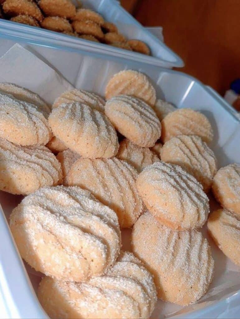 Galletas de queso crema caseras espolvoreadas con azúcar, recién horneadas y servidas en un recipiente.