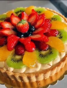 Tarta de frutas con crema pastelera decorada con frutillas, kiwi, durazno y arándanos sobre una masa sablée dorada.