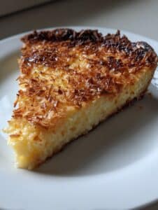 "Rebanada de Tarta Saludable de Cottage, Limón y Coco sin gluten, con coco rallado dorado por encima"